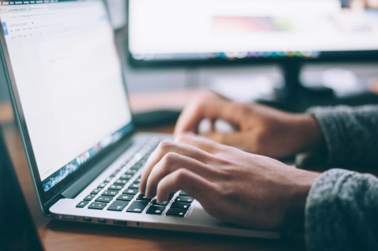 Best AI writing assistants for bloggers featured image of a laptop and notebook